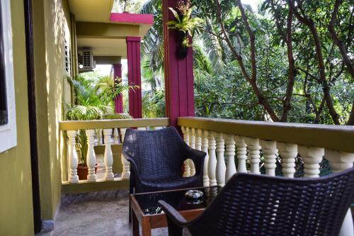 a balcony with two chairs and a window with trees at LaligurasVilla Beachside Escape - 100m to Beach in Candolim