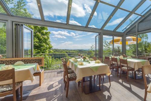 a conservatory with tables and chairs and glass windows at Gasthof Krone Hotel & Restaurant in Friedrichshafen