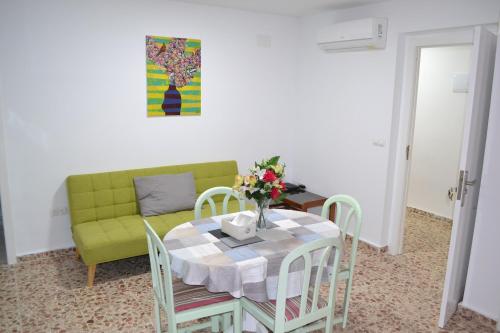 ein Esszimmer mit einem Tisch und einem grünen Sofa in der Unterkunft Gran Notch in Alicante