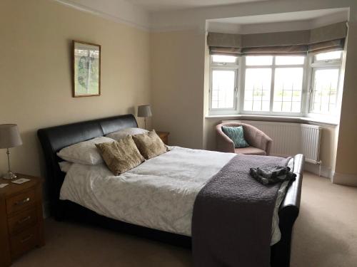 a bedroom with a bed and a chair and windows at Grange House Bed & Breakfast in Lowdham