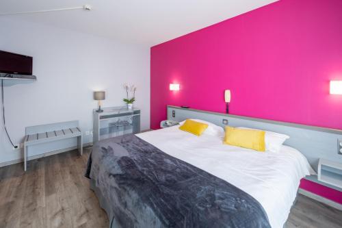a bedroom with a large bed with a pink wall at Hôtel du Soleil Levant in Argelès-Gazost
