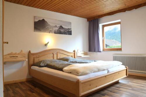 a bedroom with a wooden bed with a window at Pension Lichtspitze in Häselgehr