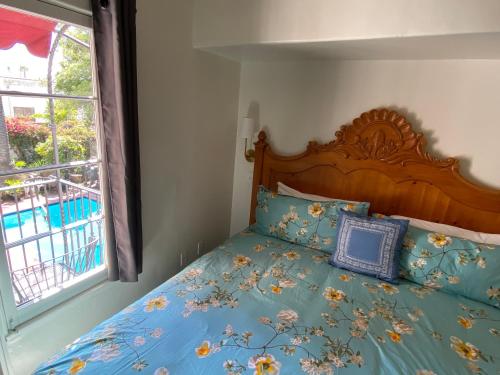 a bedroom with a bed with blue sheets and a window at Villa Rosa Inn in Santa Barbara