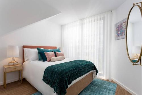 a white bedroom with a bed with a green blanket at STUPENDO-One room concept-Center-Air conditioning in Lisbon