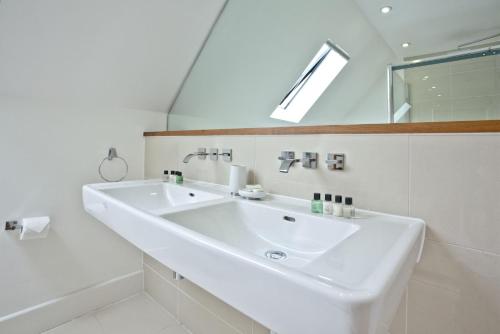 a white bathroom with a sink and a mirror at 10 The Whitehouse, Watergate Bay in Porth