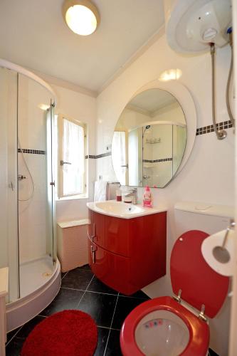 a bathroom with a red toilet and a sink at Villa MT in Posedarje