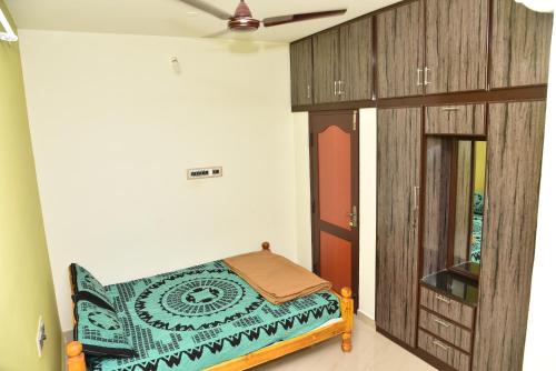 a room with a bed and a wooden cabinet at Thirumalai Home Stay - Group & Family Stay Room VL Swami Malai Temple in Kumbakonam