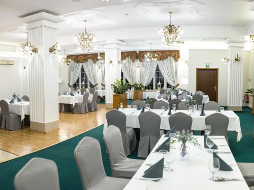 ジェシュフにあるHotel Villa Rivieraの白いテーブルと椅子、シャンデリアが備わる宴会場