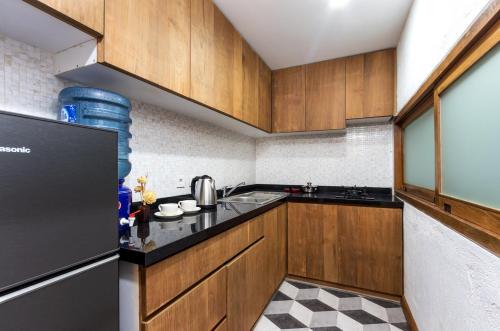 a kitchen with wooden cabinets and a black refrigerator at Ruang Tekuni in Legian