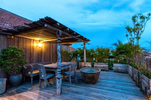a wooden deck with a table and a wooden pergola at Ruang Tekuni in Legian