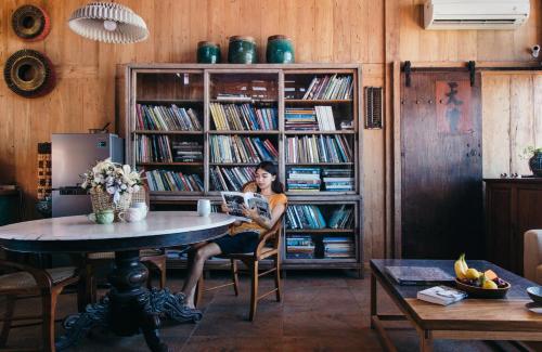 a woman sitting at a table reading a book at Ruang Tekuni in Legian