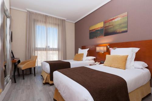 a hotel room with two beds and a window at Hotel Puerta de Toledo in Madrid