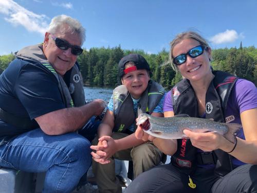 a group of people sitting on a boat with a fish at Pourvoirie du Lac Blanc in Saint-Alexis-des-Monts