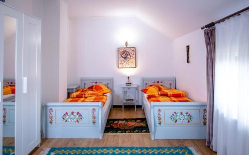 a bedroom with two beds with orange pillows at Pensiunea Curtea lui Toader in Simioneşti