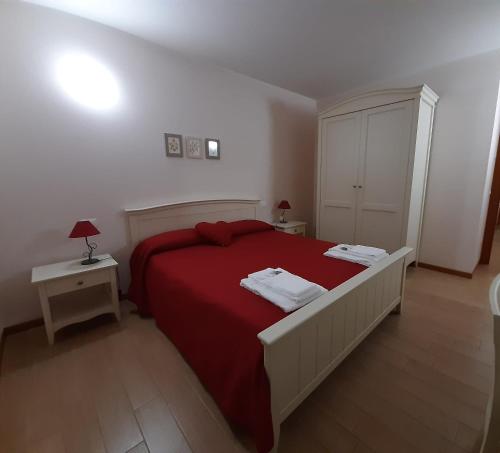 1 dormitorio con 1 cama grande de color rojo y 2 mesas en Albergo Diffuso Polcenigo C.Barnard, en Polcenigo