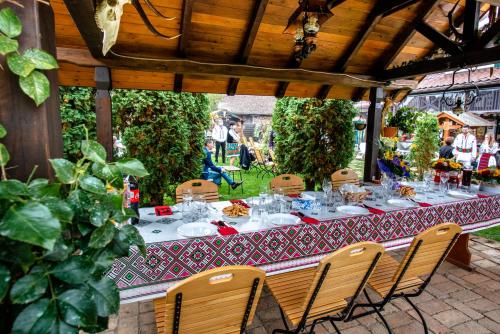 a table with chairs and plates of food on it at Pensiunea Curtea lui Toader in Simioneşti