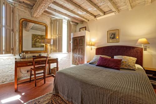 a bedroom with a bed and a desk with a mirror at Les Jardins de Baracane in Avignon