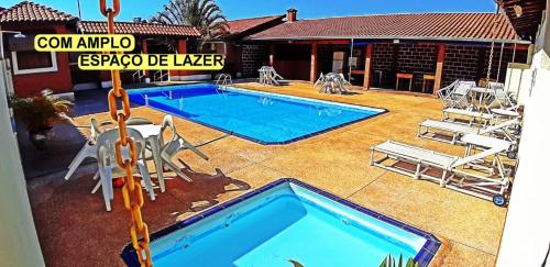 a swimming pool in a yard with chairs and a house at Pousada Portal in São Pedro