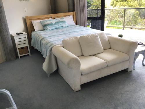 a bedroom with a bed and a white couch at Heads Up in Mangawhai