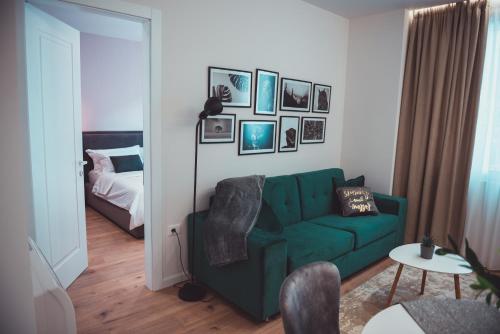 een woonkamer met een groene bank en een bed bij TAM Serviced Apartments City Center No2 in Tirana