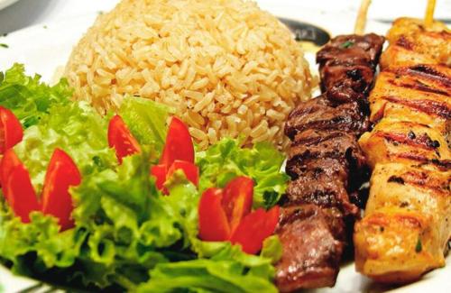 a plate of food with rice and meat and salad at Hotel Triângulo in Caldas Novas