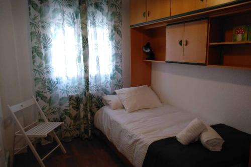 1 dormitorio con 1 cama, 1 silla y 1 ventana en Alojaguay RONDILLA, en Valladolid