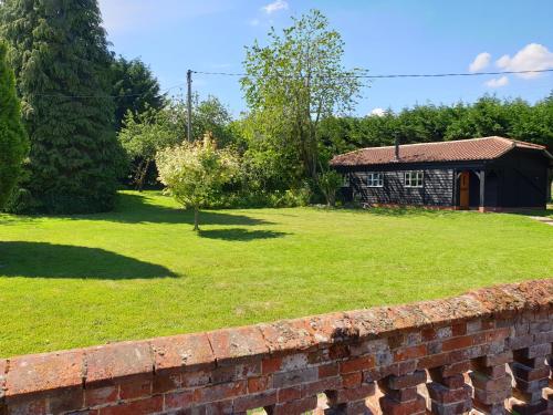 a yard with a brick wall and a house at Church Farm Lodge in Southburgh