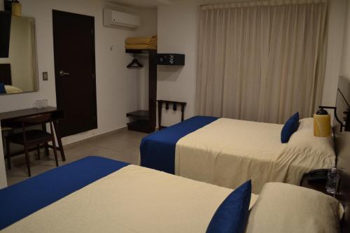 a hotel room with two beds and a desk at Hotel Real Alma in Oaxaca City