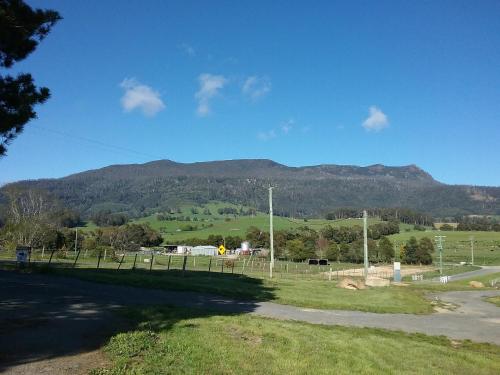 a field with a fence and mountains in the background at Meander Country Cabins in Meander