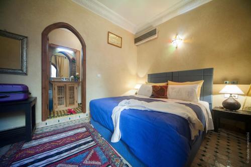 a bedroom with a blue bed and a mirror at Riad Bab Tilila in Marrakech