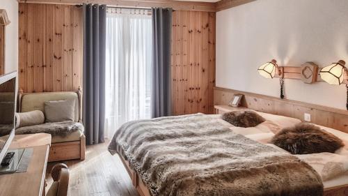 a bedroom with a bed and a chair and a desk at Hotel La Cambuse in Les Collons