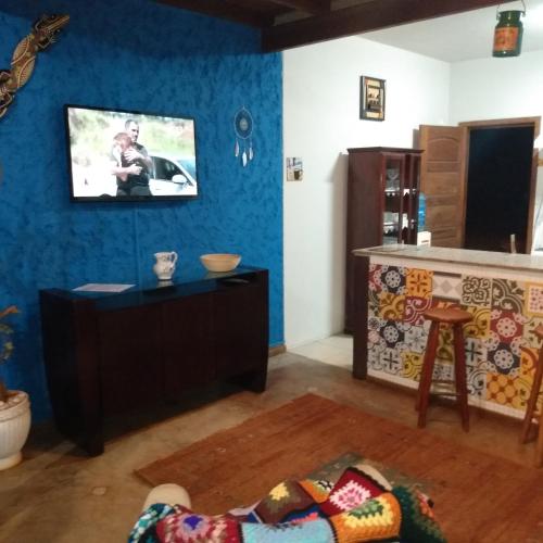 a living room with a tv on a blue wall at Chalé Cores da Mata in Brumadinho