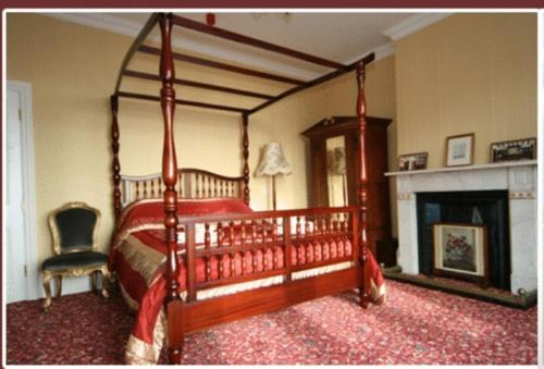 a bedroom with a canopy bed and a fireplace at Britten House in Lowestoft