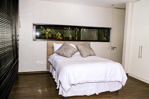 a bedroom with a white bed with a window at Ten On Lane in Polokwane