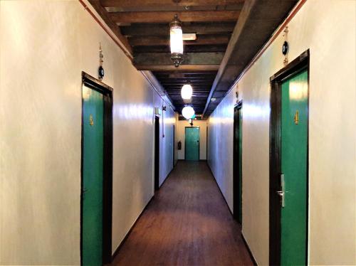 an empty hallway with green doors and wooden floors at Blue Eyes Hotel in Kepala Batas