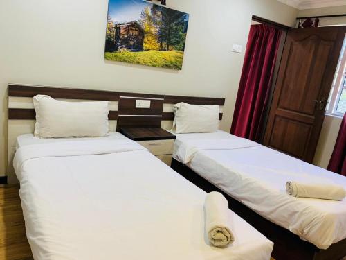 two twin beds in a room with a window at Zermatt Hotel in Cameron Highlands