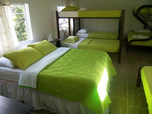 a bedroom with three bunk beds with green sheets at Club campestre el Peñón de Apulo in Apulo