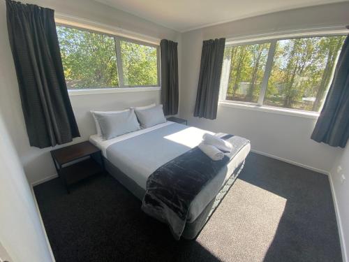 a bedroom with a bed and two windows at LINEA on Aorangi in Lake Tekapo
