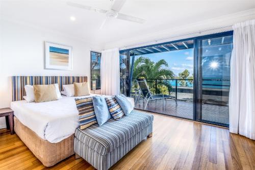 a bedroom with a bed and a couch and a balcony at Shorelines in Hamilton Island