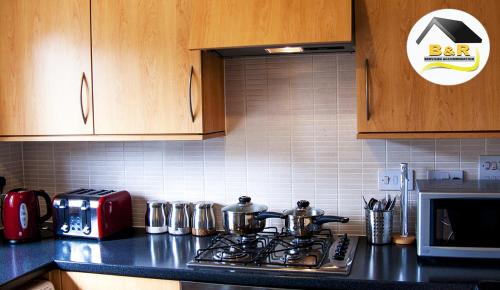 a kitchen counter with pots and pans on a stove at B and R Serviced Accommodation, 3 Bedroom House with Free Parking, Super fast Wi-Fi 145Mbps and 4K smart TV, Barnard House in Amesbury