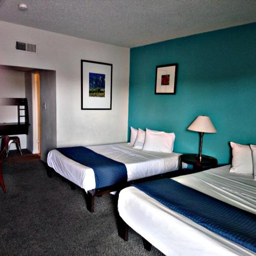 two beds in a hotel room with blue walls at Desert Hills Motel in Las Vegas