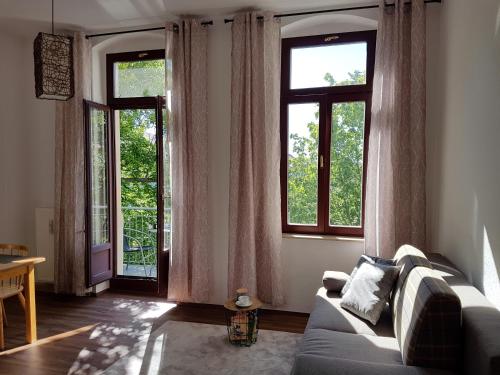 ein Wohnzimmer mit einem Sofa und 2 Fenstern in der Unterkunft Stilvolle 1-Raum-Wohnung zentral, ruhig gelegen in Dresden