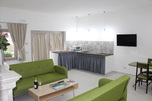 a living room with green furniture and a kitchen at LE CANONICHE NEL MATESE ALBERGO DIFFUSO in San Massimo