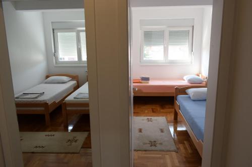 a room with two beds and a table and two windows at Al Maha in Banja Koviljača
