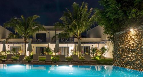 a hotel with a swimming pool at night at The B Resort in Kampot