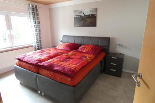 ein Bett mit roten Kissen im Schlafzimmer in der Unterkunft Ferienwohnung Römerweinhof in Neumagen-Dhron