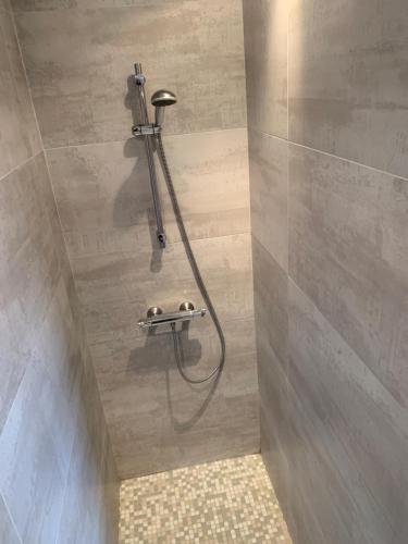 a shower in a bathroom with a hose on the wall at La Fleur de Sel in La Flotte