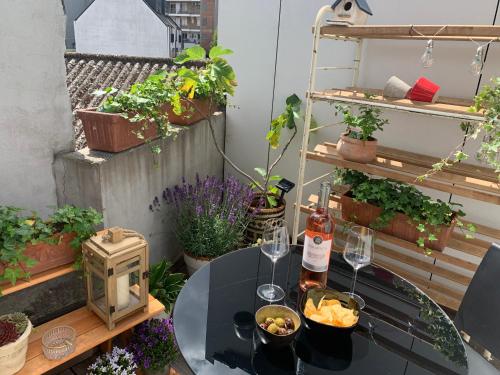 a table on a balcony with wine glasses and plants at Violet Suites in Ghent
