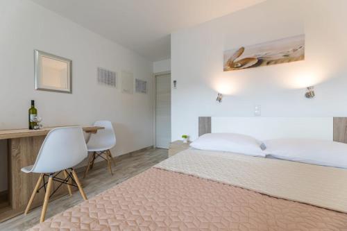 a bedroom with a bed and a desk with two chairs at Apartments Augustinovic in Baška