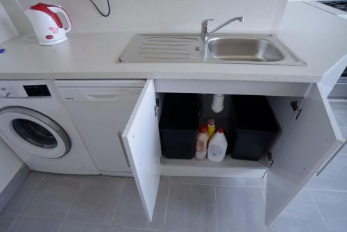 a white kitchen with a sink and a washing machine at Apartmány Karviná in Karviná